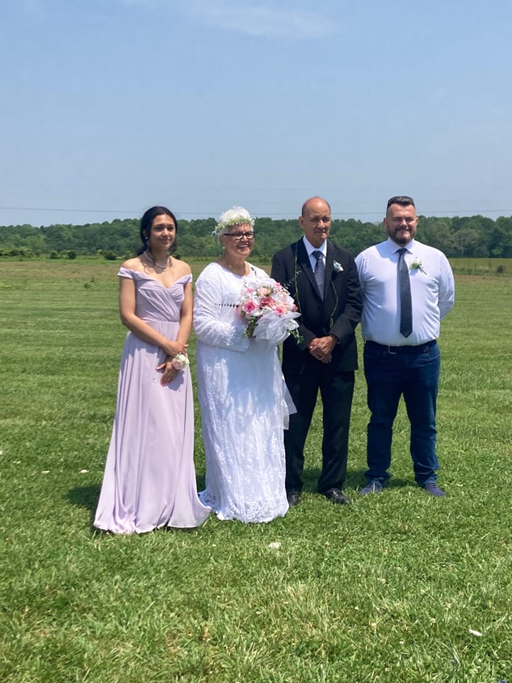 A bride and groom pose for a photo with two parents.