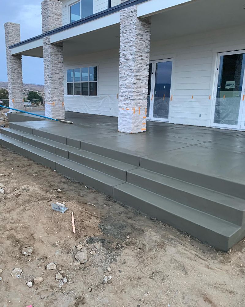 A new home shows a freshly poured concrete patio with three levels of steps.