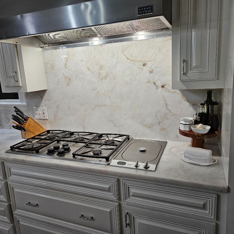 A kitchen stove with a granite countertop and backsplash.