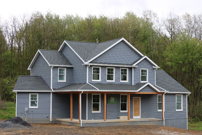 A newly built gray home with a gray roof and new white windows.