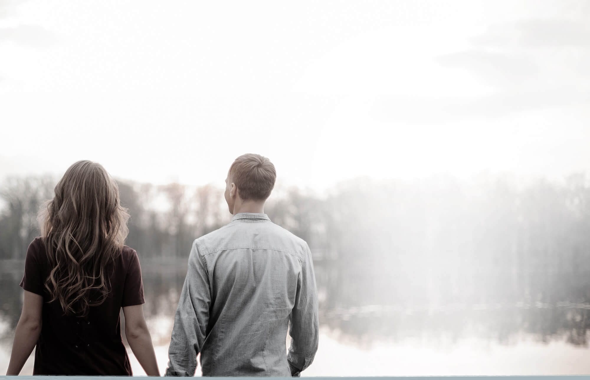 man and woman looking out on a river holding hands