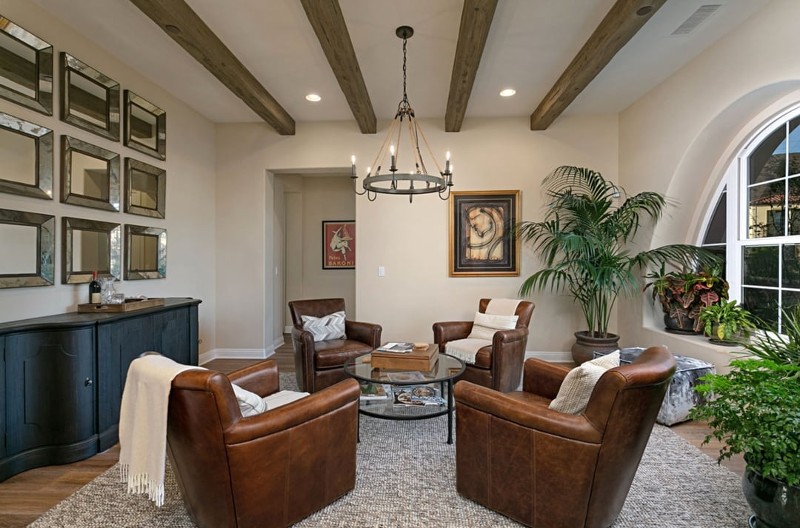 Remodeled den with leather chairs, plush rug, plants, decorative ceiling beams
