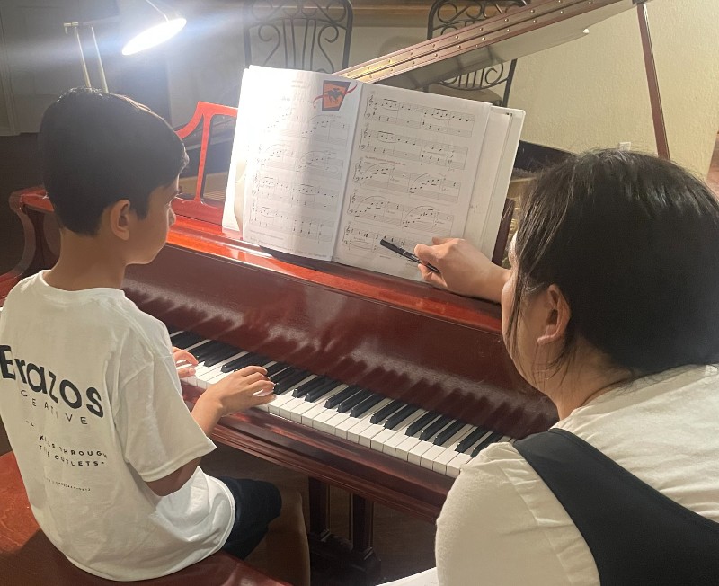 Instructor teaching a young boy to play piano.