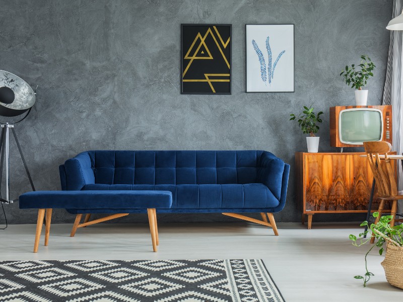 A sitting area with a blue couch and a wooden TV stand.