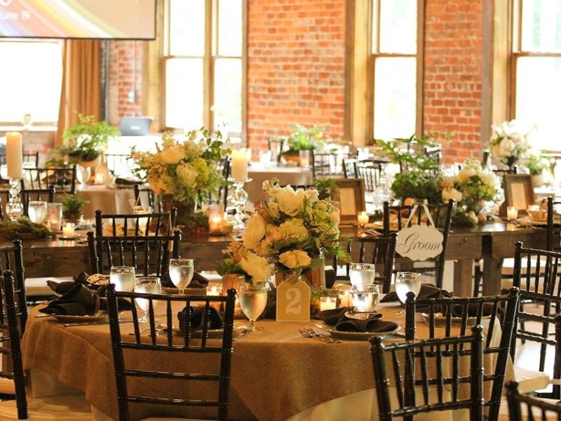 AN elegant event space with hardwood floors, brick walls, tables, chairs