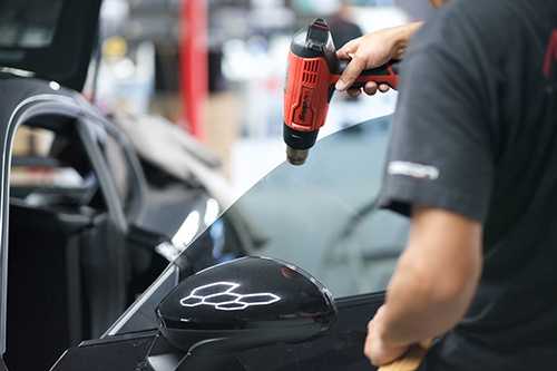 A man air dries detailing on a car.