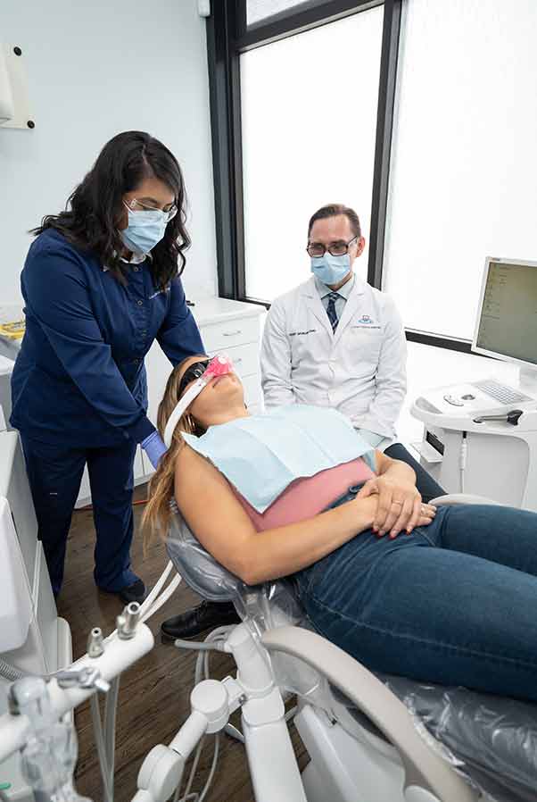 A dentist prepares a patient for sedation.