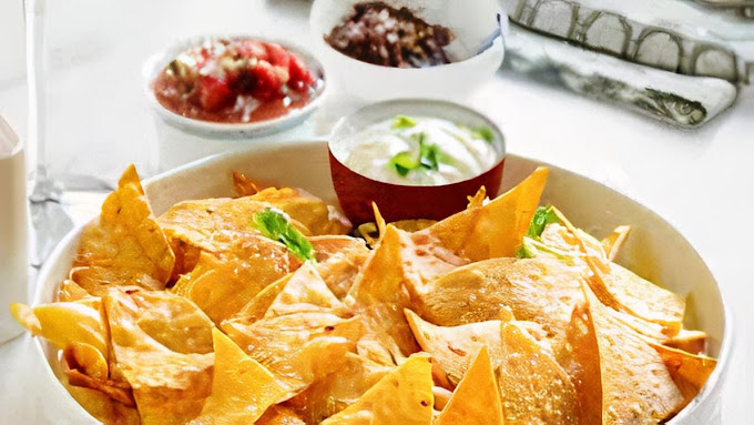 A bowl of nacho chips with queso sauce.