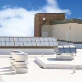 A white industrial roof with sky lights and a cooling system