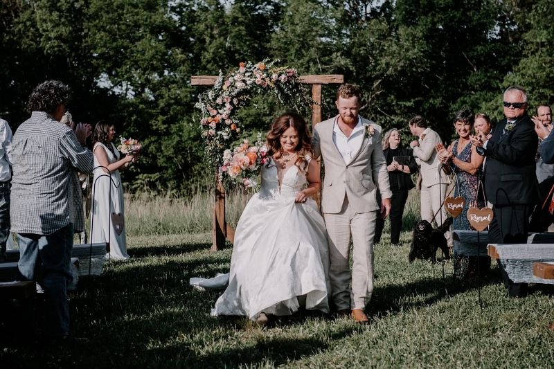 A bride and groom walk past wedding guests following their wedding ceremony.