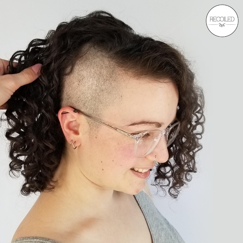 A young woman with curly hair and an undercut shows off her new look