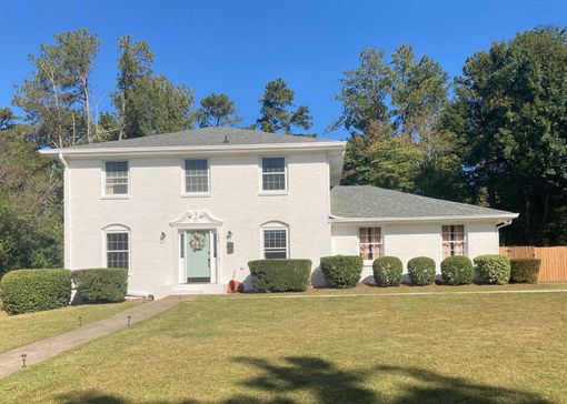 Exterior view of a freshly painted white brick home.