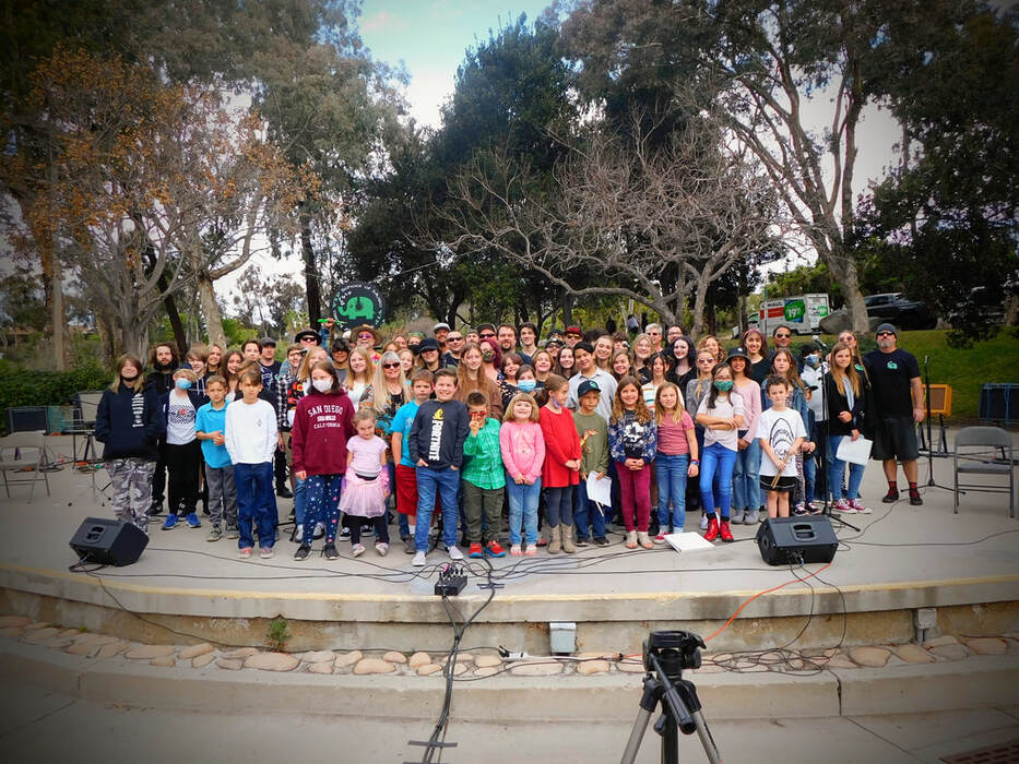 A large group of youngsters poses for a photo outside.