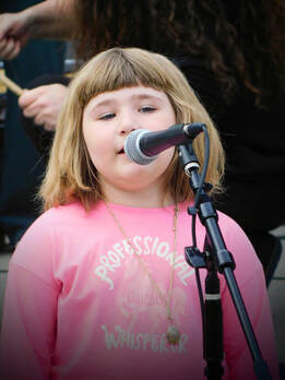 A young girl sings into a microphone.