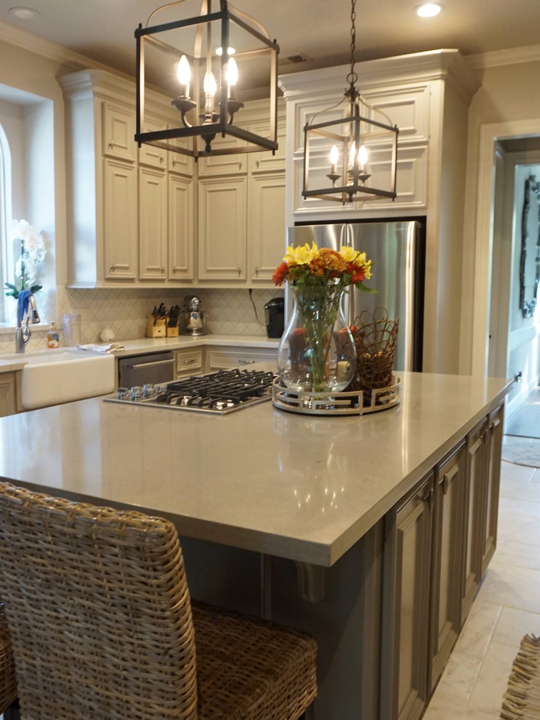 A kitchen scene featuring an island with quartz countertop and tile backsplash and flooring.