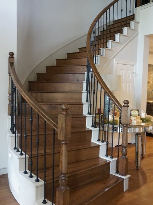 A curved staircase features beautiful dark hardwood flooring.