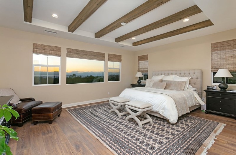 remodeled master suite with wood flooring, picture windows, king bed, decorative ceiling beams