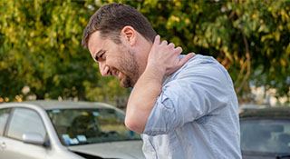 A man reaches for his neck in pain.