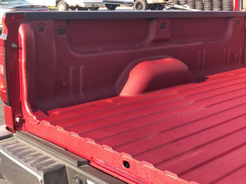 A pickup truck with a red spray-on bed liner.