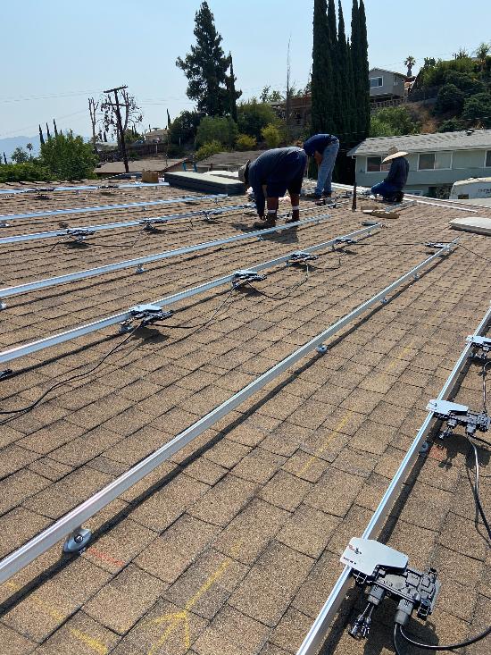 Crew members work to install a large solar power system on a home's roof.