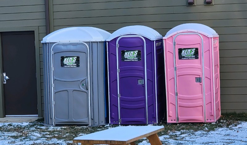 A row of three colorful portable toilets.