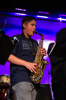 A young boy plays the saxophone.