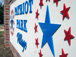 An outdoor sign between brick columns for Patriot Park Village.