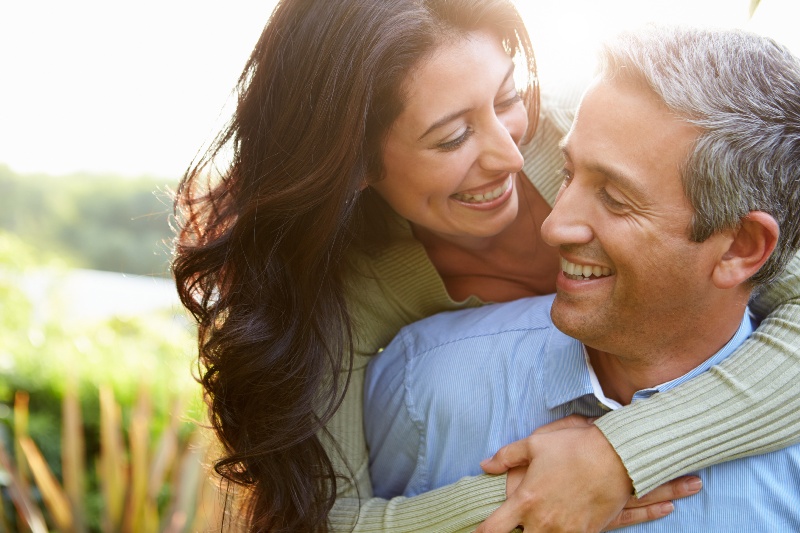 A woman embraces a man around the shoulders