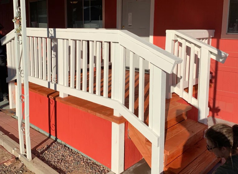 Newly constructed front porch with white wooden railings.