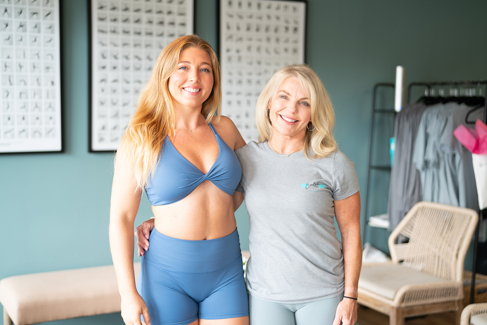 Two women smile with their arms around each other.