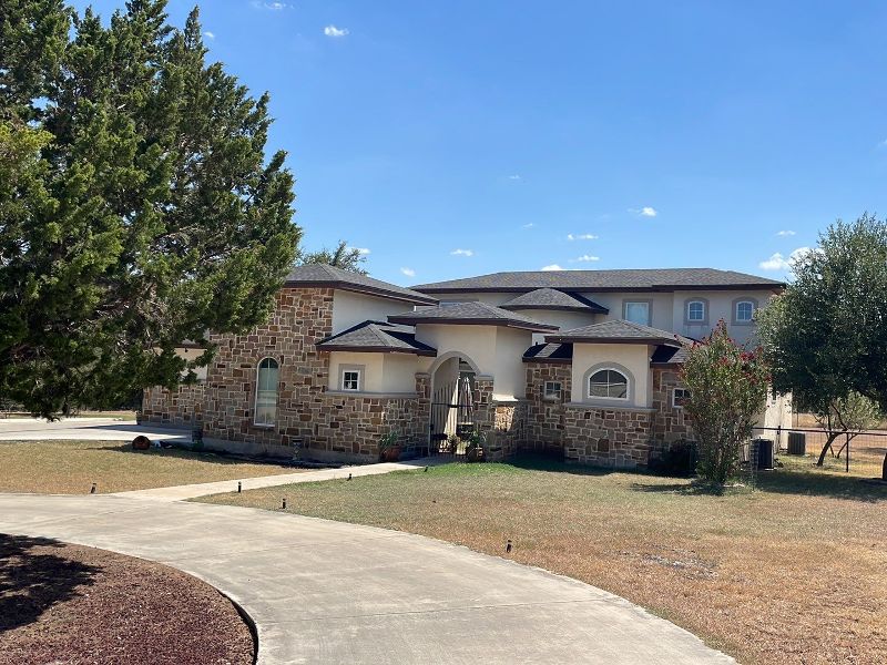 A large home sits behind an entrance gate with a shingle roof.