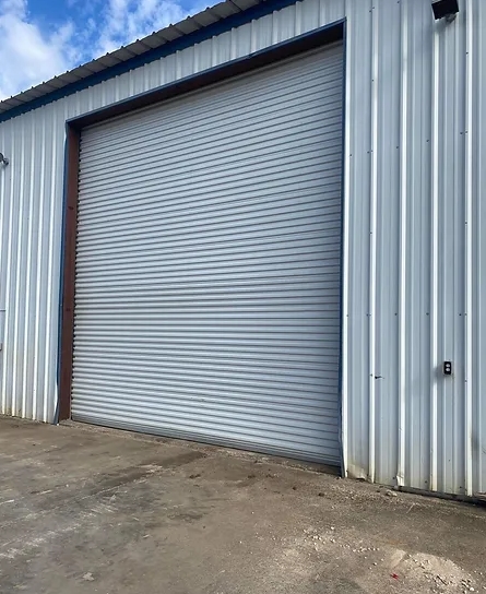 Large white metal roll-up door on a white metal building.