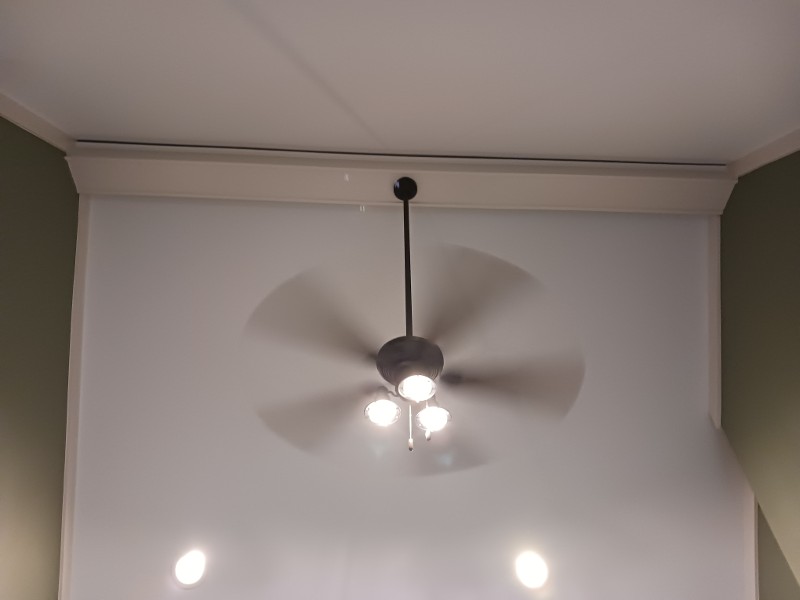 A freshly painted wall with a ceiling fan in motion.