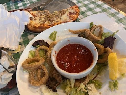 Fried calamari appetizer with marinara and a pizza on a table at an Italian restaurant, green and white checkered table cloth