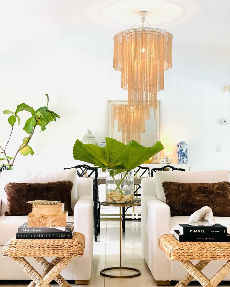 A sitting area with side tables and a plant stand in between two chairs.