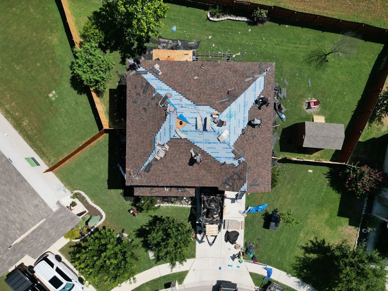 The overhead view of a singled roof with tarp covering sections of damage.