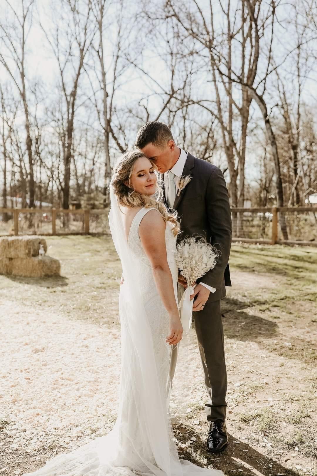 A groom leans over to put his forehead on his bride's face.