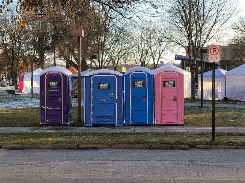 A row of four colorful portable toilets.