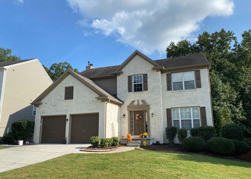 Exterior view of a tan brick home with brown shutters.