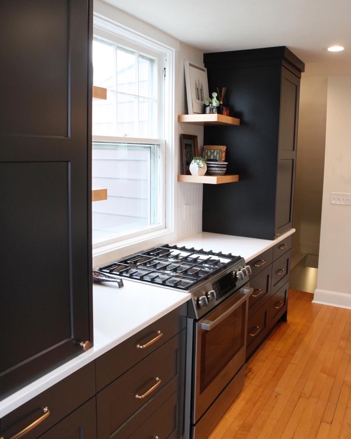 One wall of a kitchen with dark wood cabinets, gas stove, and white granite countertops.