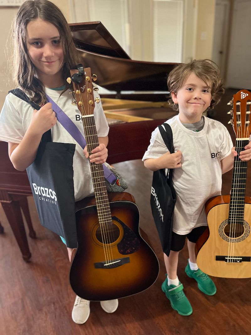 Two young guitar students posing with their instruments.