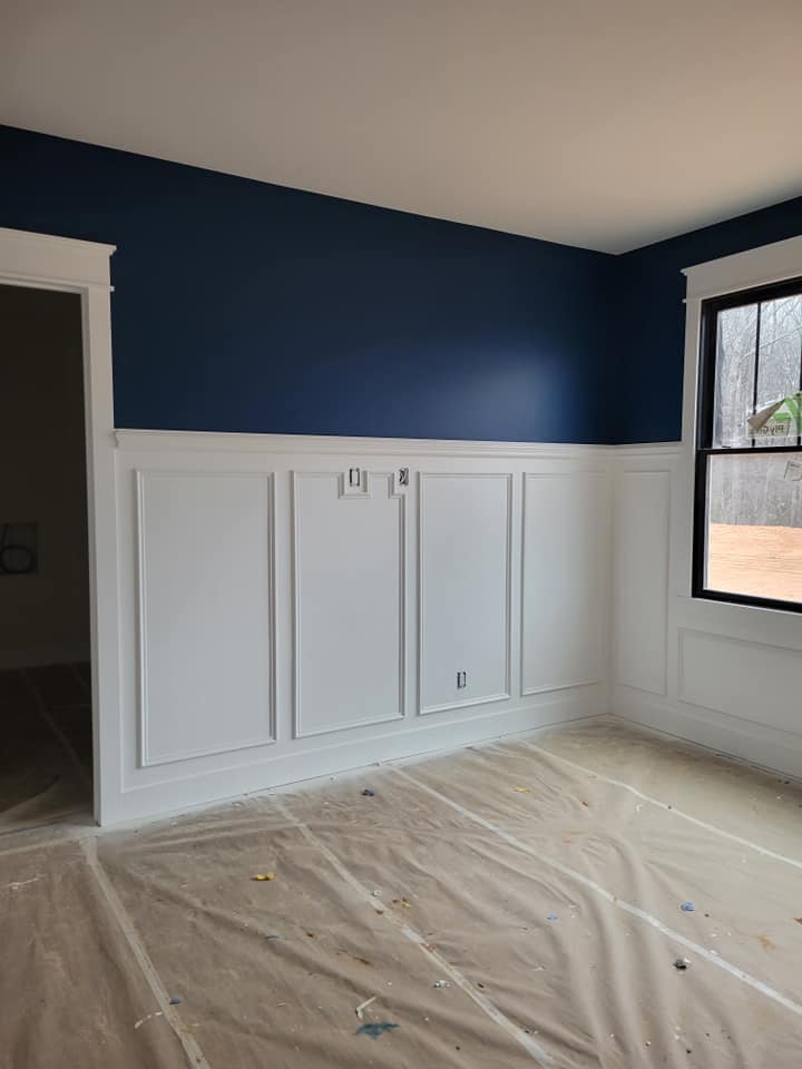 A newly painted dining room with blue on top and white on bottom with a chair rail and the flooring covered in plastic.