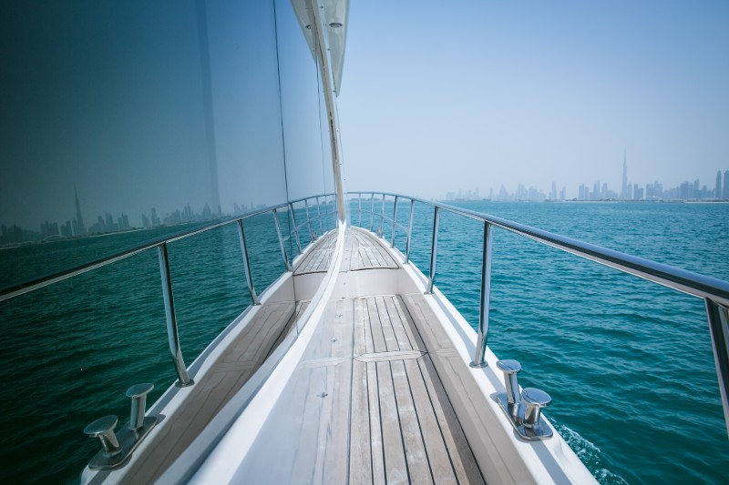 The view from a cruiser boat as it heads out to water near a city skyline with a reflection showing in the boat windows.