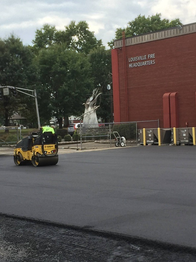 A small asphalt roller sits in a parking lot.