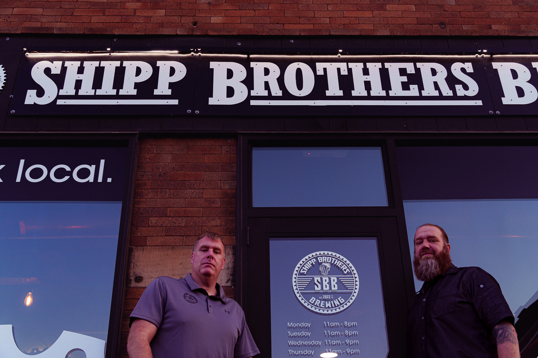 Owners of Shipp Brothers Brewing posing outside their front door..