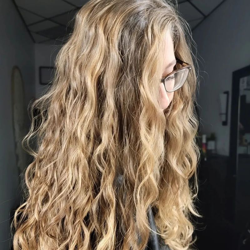 A woman with long curly blonde hair shows off her new cut and style