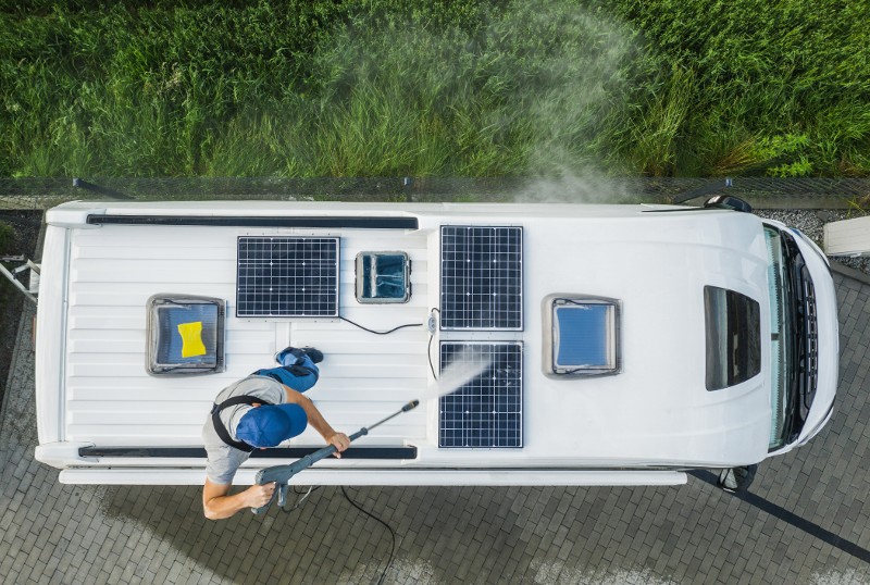 A man power washes the top of his RV.