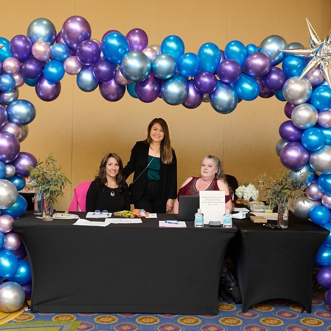 three women smiling at balloon-decorated table