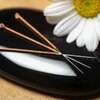 Acupuncture needles lay next to a daisy.