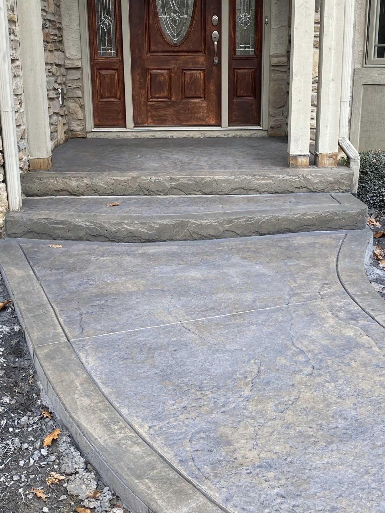 A stamped concrete sidewalk leads to a door entry with two steps.